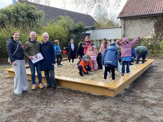 Anne Janßen von der Kreissparkasse Steinfurt, Hausmeister Dariusz Tomkiewicz und Schulleiterin Sabine Knuf weihen den neuen Sandkasten der Grundschule Stadt offiziell ein.